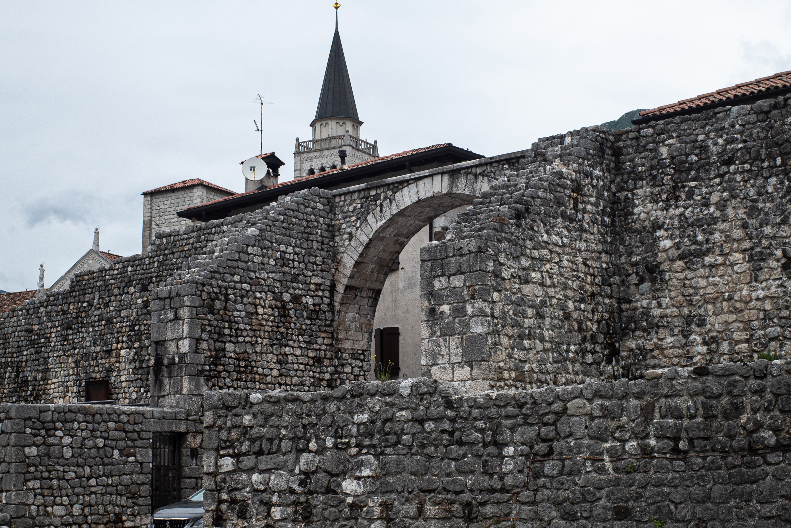 Die Stadtmauer von Venzone mit ihrem Torbogen, dahinter der Kirchturm
